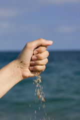 hand with little stones over blue sky and ocean