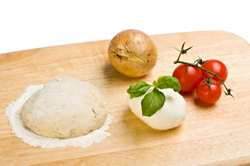Hefeteig, Käse, Tomaten und Zwiebeln auf einem Holzbrett