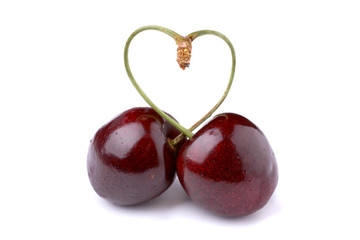 Pair of cherries tied into a heart over white background
