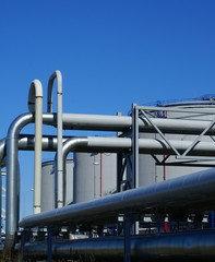 industrial pipelines and storage tanks against blue sky