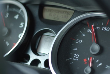 car speedometer with red arrows on black, horizontal