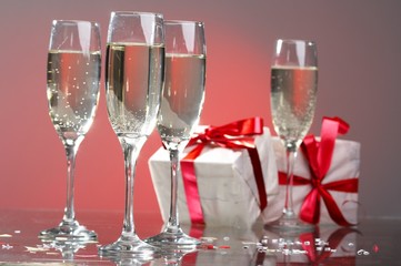 Glasses of champagne, gifts with red tapes and bows
