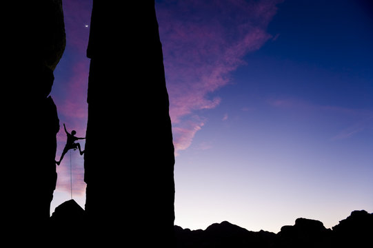 Rock climber reaching across a gap.