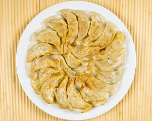Plate Full of Fried Chinese Dumplings on Bamboo Place Mat