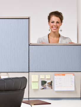 Businesswoman peering over cubicle wall