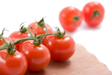 ripe tomatoes over wood board isolated
