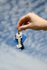 hand with key on the blue sky background