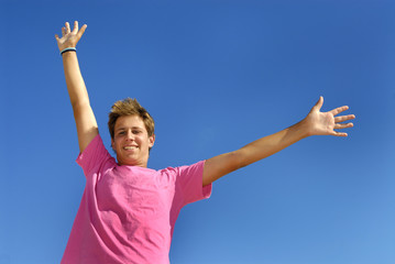 Boy arms wide open against a blue sky