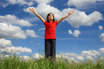 Kid holding arms up in praise against blue sky