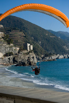 Parapendio in fase di atterraggio con sfondo la costa