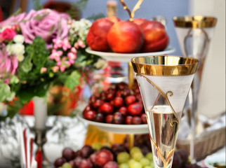 Glass with champagne against a bouquet and fruit
