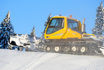 Ski slope with a yellow ratrak doing track maintenance