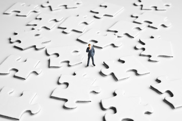 Businessman figurine surrounded by puzzle pieces