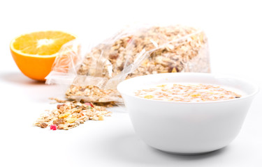 a bowl of muesli with milk with a bag of muesli and an orange