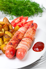 sausages wrapped in bacon, roasted potatoes, sliced tomatoes