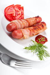sausages wrapped in bacon and sliced tomatoes