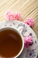 Obraz na płótnie Canvas cup of tea and flowers over bamboo mat