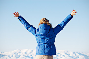 view from behind on happy woman against sky and mountains