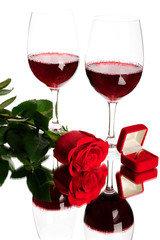 Two glasses of red wine, rose and wedding ring isolated on white