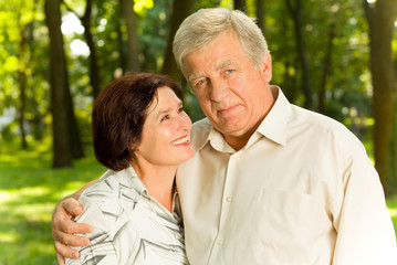Senior attractive happy couple embracing in park