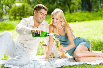 Young happy couple celebrating with champagne at picnic