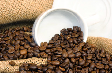 Coffee beans, burlap and a white cup