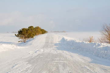 A bad weather on rural road.  Glaze ice,  snowdrift.