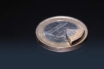 Euro coin and coin's part lying on dark background