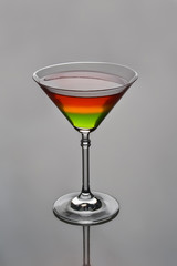 Glass of tricolor cocktail on grey