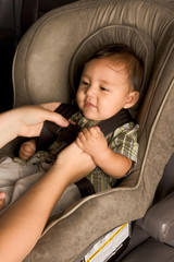happy ethnic Asian baby boy child put in carseat