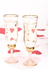 two glasses  of white wine on white heart covered background