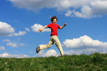 Boy running, jumping against blue sky