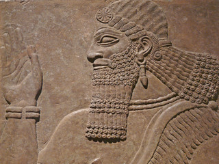 Ancient Assyrian wall carving of a man showing his head and hand