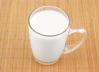 Glass cup of milk on wooden placemat
