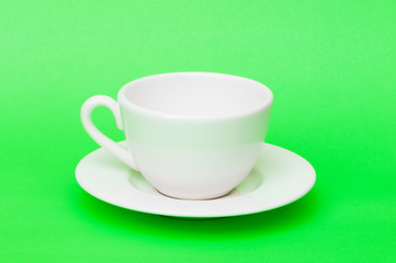 White tea cup isolated on green background