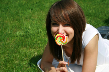 Girl eats lollipop on lawn