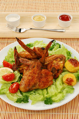 Grilled chicken wings with baked potatoes and vegetable salad