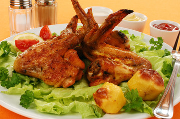 Grilled chicken wings with baked potatoes and vegetable salad