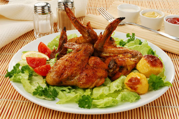 Grilled chicken wings with baked potatoes and vegetable salad