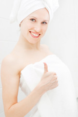 young woman in white towels showing thumbs up
