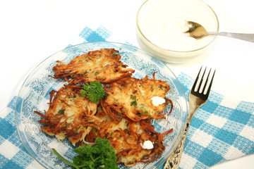 Potato pancakes , served with sour cream. Isolated.