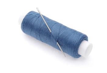 The coil of blue threads with needle on white background