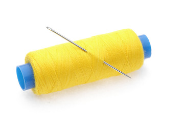 The coil of yellow threads with needle on white background