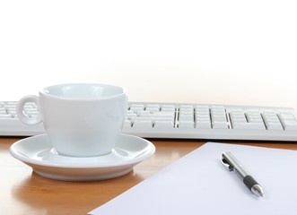 Cup of coffee, keyboard and pen on a table in office