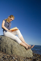 Frau am Strand liest ein Buch