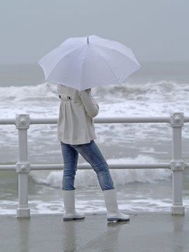 Chica con paraguas mirando al mar