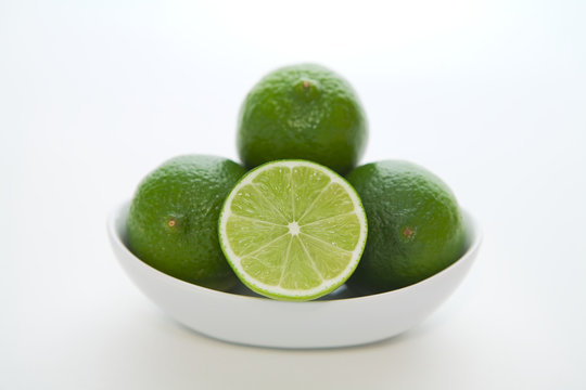 Simple bowl of limes geometrically stacked with white background