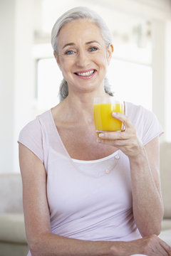 Senior Woman Holding Orange Juice And Smiling At The Camera