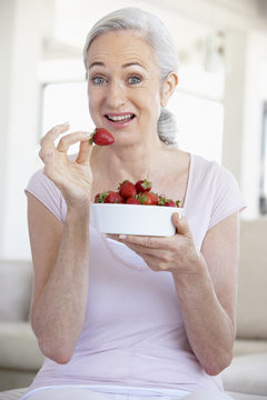 Senior Woman Eating A Bowl Of Strawberries