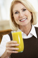 Senior Woman Drinking A Glass Of Fresh Orange Juice